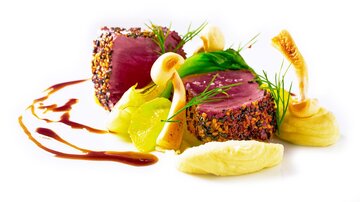 Ein kunstvoll angerichtetes Gericht mit zartem Fleisch, umgeben von buntem Gemüse und einer feinen Sauce. Die Präsentation ist elegant und einladend.