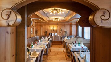 Ein gemütliches Restaurant mit Holzinterieur und elegant gedeckten Tischen. Sanftes Licht beleuchtet den Raum und schafft eine entspannte Atmosphäre.