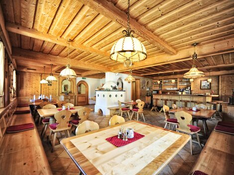 A cozy restaurant with wooden decor and warm lighting. The tables are neatly set and provide space for guests.