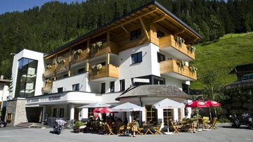 Ein gemütliches Hotel mit einem modernen und traditionellen Design. Es gibt eine Terrasse mit Tischen und Stühlen sowie einen schönen Blick auf die umliegenden Berge.
