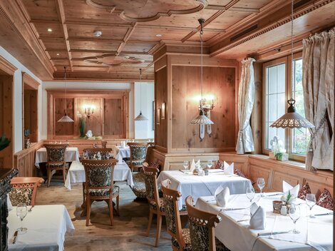 A cozy restaurant with wooden walls and elegantly set tables. Soft lighting creates an inviting atmosphere.