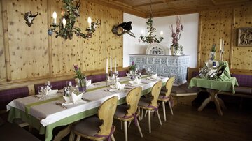 Ein gemütliches Restaurant mit Holzwänden und rustikaler Einrichtung. Tische sind liebevoll gedeckt und eine warme Atmosphäre lädt zum Verweilen ein.