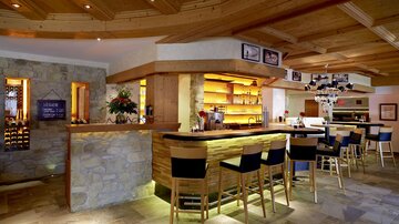 Eine gemütliche Bar mit Holzdekor und eleganten Stühlen. Der Raum ist hell erleuchtet und lädt zum Verweilen ein.