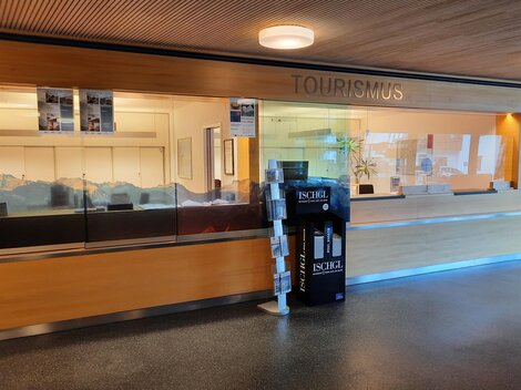 A reception area for tourism with a glass wall. On the floor, there is an information stand about the Ischgl region.