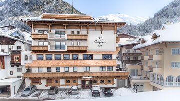 Ein modernes Hotel im alpinen Stil, umgeben von schneebedeckten Bergen. Die Fassade zeigt Holzdetails und große Fenster.