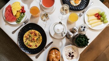 Ein reichhaltiges Frühstücksbuffet mit frischem Obst, Eiern, Omelett und verschiedenen Getränken. Die Auswahl ist bunt und ansprechend angerichtet.