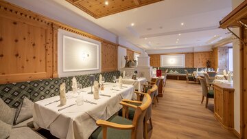Ein elegantes Restaurant mit Holzwänden und gemütlicher Atmosphäre. Die Tische sind schön gedeckt und laden zum Verweilen ein.