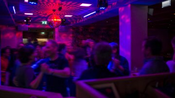 Eine lebhafte Party in einem Club mit buntem Licht. Menschen tanzen und haben Spaß in einer ansprechenden Atmosphäre.