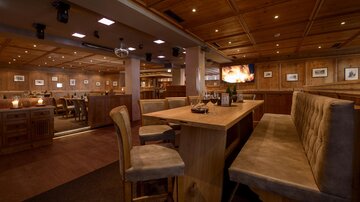 Ein gemütliches Restaurant mit Holzmöbeln und warmem Licht. Die Atmosphäre wirkt einladend und entspannt.