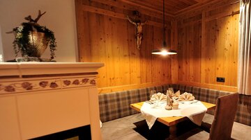 Ein gemütlicher Essbereich mit Holzwänden und einem warmen Ambiente. Der Tisch ist schön gedeckt, und ein Kamin sorgt für eine einladende Atmosphäre.