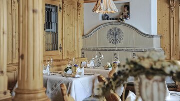Ein gemütliches Restaurant mit Holzvertäfelung und eleganten Tischdekorationen. Sanftes Licht von der Deckenlampe sorgt für eine einladende Atmosphäre.