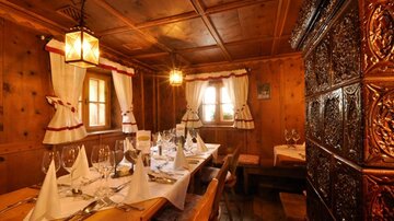Ein gemütliches Restaurant mit Holzvertäfelung und traditioneller Dekoration. Der Tisch ist festlich gedeckt und schafft eine einladende Atmosphäre.
