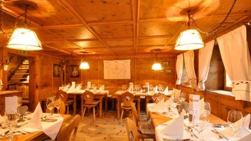 Ein gemütliches Restaurant mit Holzmöbeln und warmem Licht. Die Tische sind elegant gedeckt und laden zum Verweilen ein.