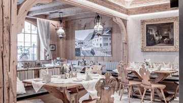 Ein gemütliches Restaurant mit Holzdekor und rustikalen Möbeln. Die Tische sind schön gedeckt und es gibt dekorative Kunstwerke an den Wänden.