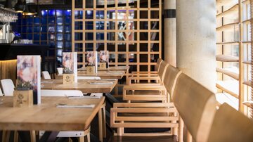 Ein modernes Restaurant mit Holztischen und -stühlen. Die Einrichtung ist stilvoll und wirkt einladend.